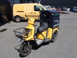 un scooter garé sur un parking, avec une camionnette jaune en arrière-plan