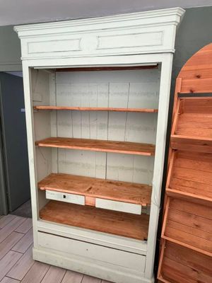 a tall white bookcase with two drawers and a shelf