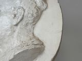 a sculpture of a man ' s head on a white surface