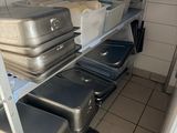 several suitcases are stacked on a metal rack in a kitchen