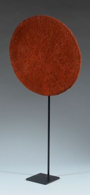 a red circular sculpture on a black stand