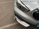 the front end of a silver car with a number plate on it