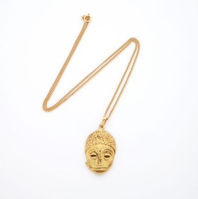 un collier en or avec un pendentif en forme de visage, monté sur une chaîne