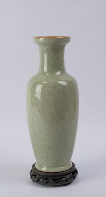 un vase vert posé sur un socle, sur une surface blanche