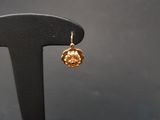 a close up of a pair of gold earrings on a black stand