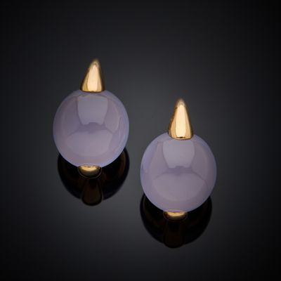 a pair of white jade and gold earrings on a black surface