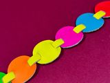 a close up of a colorful paper chain on a pink surface