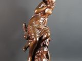 statue en bronze représentant une femme tenant un oiseau, posée sur une table noire