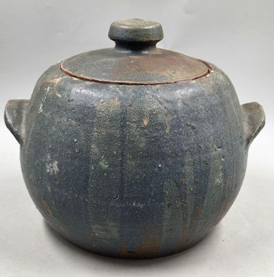 un pot bleu avec un couvercle posé sur une surface blanche