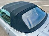 une voiture de sport argentée à la capote noire, garée sur un parking