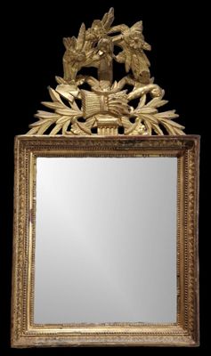 un miroir avec un cadre doré sur lequel est représenté un oiseau