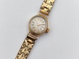 gros plan d'une montre-bracelet en or sur une surface blanche