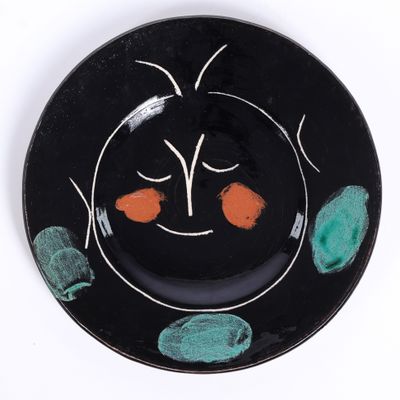 une image représentant une assiette noire sur laquelle est peint un visage