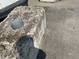 a stone block sitting on the side of the road next to a car