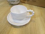 a cup and saucer sitting on a table with a box in the background