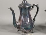 two silver teapots sitting next to each other on a table