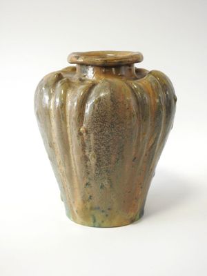 un vase marron avec un couvercle, posé sur une surface blanche