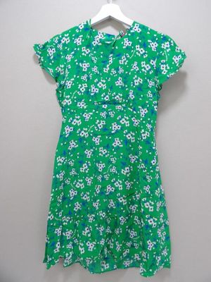 a green dress with white flowers on it hanging on a hanger