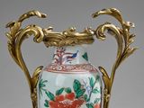 a vase that has a gold handle on it