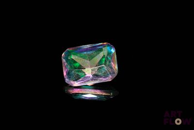 a close up of a green and purple diamond on a black surface