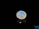 une pierre de lune posée sur une surface noire, sur fond noir