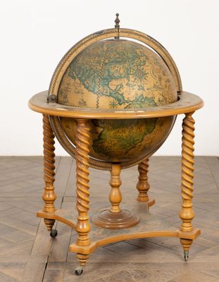 un vieux globe posé sur un socle en bois, sur un sol carrelé