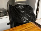une table en bois sur laquelle est posé un sac en plastique noir