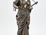 an antique bronze statue of a woman playing a guitar