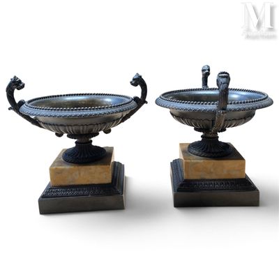 une paire d'urnes antiques en bronze posées sur des socles en marbre, sur fond blanc