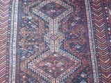 an old persian rug with a geometric design on a wooden floor