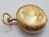 a gold pocket watch with a chain on a white surface