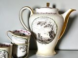 three cups and a teapot sitting on a table