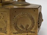 a gold clock that is sitting on a stand