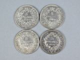 four silver coins sitting on top of each other on a white surface