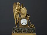 une statue en or représentant un ange, avec une horloge posée sur une table