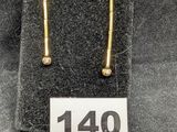 un gros plan sur une paire de boucles d'oreilles en or posées sur un tissu noir