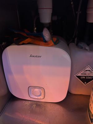 a white water heater sitting next to a bottle of beer