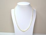necklace with white beads on a white mannequin with a beige background