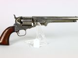 un vieux pistolet avec une poignée en bois sur une surface blanche