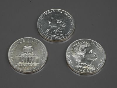 Trois pièces différentes sont représentées sur une table avec un fond gris.