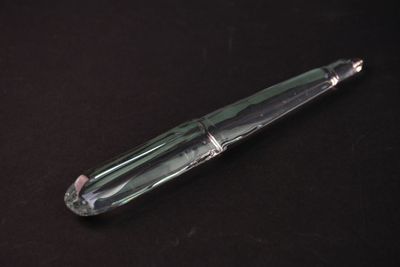 un stylo en verre posé sur une surface noire