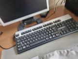 a computer keyboard and a monitor on a desk