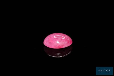une photo d'une pierre rose posée sur une surface noire
