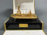 a gold and black box with a boat inside of it