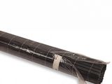 un fagot de brindilles enveloppé dans du papier noir posé sur une surface blanche