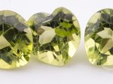 a pair of green crystal heart shaped beads on a white surface