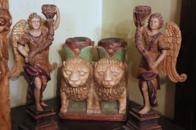 four wooden statues of angels on a shelf next to each other