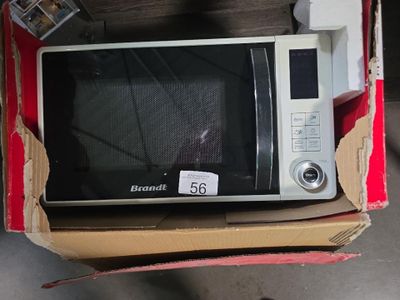 un micro-ondes qui se trouve dans un carton posé par terre