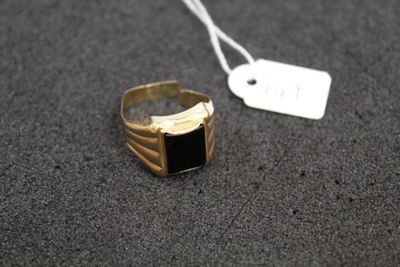 a close up of a gold ring with a black stone on it