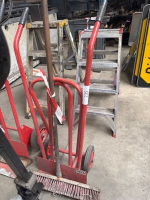 a red hand truck with a broom and a broom on it